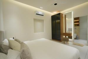 a white bedroom with a bed and a desk at Royale Suites - 1 BHK Serviced Apartment in Kadayirippu