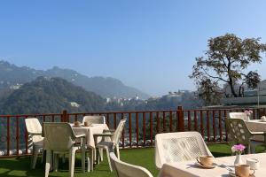 Un restaurante con mesas y sillas en un balcón. en Hotel Sunny Cot - Free Mall Shuttle and Parking, en Mussoorie