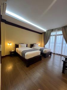 a hotel room with two beds and a large window at Pon Arena Hotel in Muang Không +80 photos