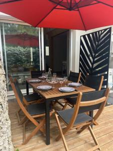 a wooden table with chairs and a red umbrella at Gite du Lac T4 in Vieux-Boucau-les-Bains