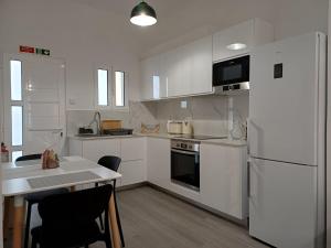 a kitchen with white cabinets and a white refrigerator at Sunset Cottage in Ponta do Sol