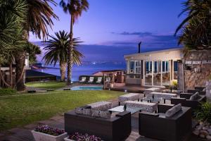 a house with couches and palm trees and the ocean at Protea Hotel by Marriott Mossel Bay in Mossel Bay