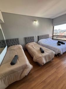 ein Zimmer mit drei Betten, auf denen schwarze Gegenstände liegen in der Unterkunft Departamento en Microcentro Ciudad de Buenos Aires in Buenos Aires