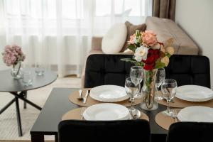einen Tisch mit Platten und eine Vase Blumen darauf in der Unterkunft Elegant Apartments Mieszczańska Wrocław with Air Conditioning, Spa & Gym by Renters Prestige in Breslau