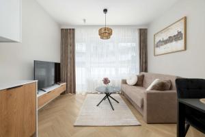 ein Wohnzimmer mit Sofa und Fernseher in der Unterkunft Elegant Apartments Mieszczańska Wrocław with Air Conditioning, Spa & Gym by Renters Prestige in Breslau