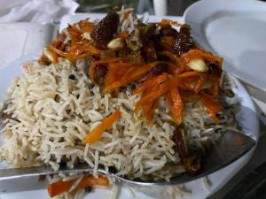 a plate of rice with meat and carrots on a spoon at Abu Dhabi Palace in Dargai