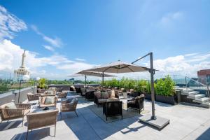 a rooftop patio with chairs and tables and an umbrella at Hotel Hampton By Hilton Santiago De Los Caballeros in Santiago de los Caballeros