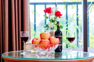 a table with two glasses of wine and a bowl of apples at Thu Ha Hotel in Uông Bí