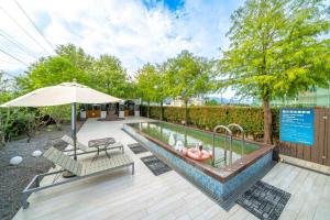 a swimming pool with an umbrella and a table and chairs at 蘭庭 Villa民宿 B&B in Yuanshan