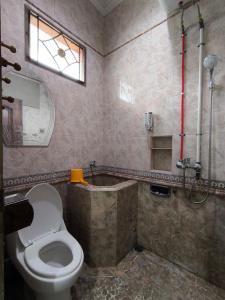 een badkamer met een toilet en een bad met een raam bij Daffodil House Proper Guest House Near Malioboro in Demangan +4 foto's