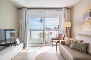 a living room with a couch and a tv and a balcony at Sitges Spaces Oasis Penthouse 3 Bedroom, 2 Bathroom, Terrace, Pool, Sleeps up to 6 in Sitges