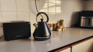 a black tea kettle on a counter next to a toaster at The Hamlet House in Prince Alfreds Hamlet