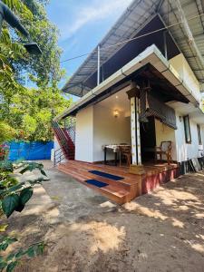 a house with a wooden deck in front of it at Marari diya homestay in Mararikulam