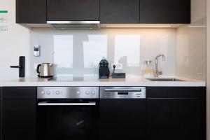 a kitchen with black cabinets and a black oven at Skyline View Vienna - Gym - Parken - Supermarkt - Restaurant - Self Check in in Vienna