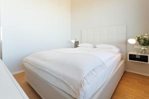 a white bed with white sheets and pillows at Skyline View Vienna - Gym - Parken - Supermarkt - Restaurant - Self Check in in Vienna
