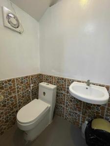 a bathroom with a toilet and a sink at Chia's Beach House Siargao in Cabalawan