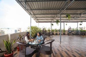 two women sitting at a table on a roof at FabHotel Frendz - Nr Hitech City Metro Station in Jāmb