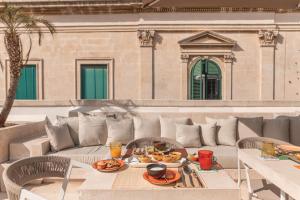 a patio with a couch and table with food on it at Palazzo Lecce - Epoca Collection in Lecce