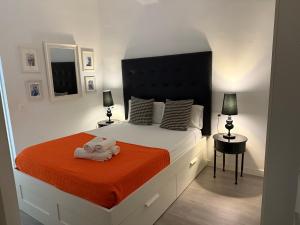 une chambre avec un grand lit avec une couverture orange dans l'établissement A 20 pasos del Museo Picasso, à Malaga