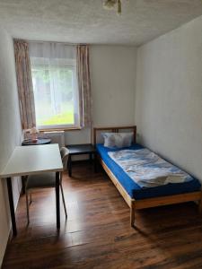 a small bedroom with a bed and a table at Bungalow 2 - 4-Raum-Wohnung mit Küche und 2 WC Duschen in Ohrdruf-Crawinkel in Niederdorla