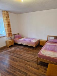 two beds in a room with wooden floors at Bungalow 2 - 4-Raum-Wohnung mit Küche und 2 WC Duschen in Ohrdruf-Crawinkel in Niederdorla