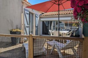 two dogs sitting on a fence with an umbrella at Spacious nest with terrace near the beach in Talmont-Saint-Hilaire