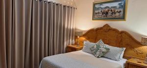 1 dormitorio con 1 cama y una ventana grande con cortinas en Mitat Guesthouse, en Beaufort West