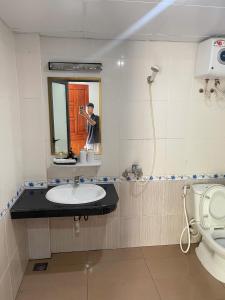 a man taking a picture of a bathroom with a sink at Manh Vuong Hotel &Travel in Cat Ba