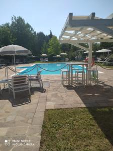 a pool with a table and chairs and an umbrella at Locanda La Cavallina in Brisighella