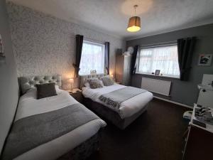a bedroom with two beds and two windows at Westbrook Lodge Guest House in Margate