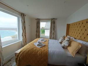 a bedroom with a bed with a large window at Ocean Edge in Sennen Cove