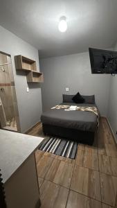 a bedroom with a bed sitting on a wooden floor at Gnostes Lodge Vosloorus in Vosloorus