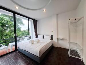 a bedroom with a bed and a large window at At Mutta Lanta House in Ko Lanta Yai