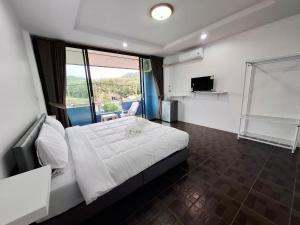 a bedroom with a white bed and a large window at At Mutta Lanta House in Ko Lanta Yai