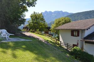 a white chair sitting in the grass next to a house at Trentino Appartamenti Oss in Tenna  +121 photos