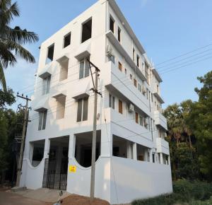a white building with a tree in front of it at Pondicherry Comfort Rooms in Puducherry