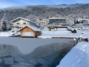 a pond covered in snow next to a building at Seehotel Hoffmann in Steindorf am Ossiacher See