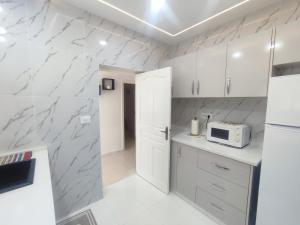 a kitchen with white cabinets and a microwave at Charmant T3 in Houmt Souk