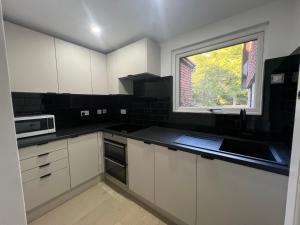 a kitchen with white cabinets and a window at Private Guest House with full kitchen living room and utility room Completely Separate from the Main House in Cobham