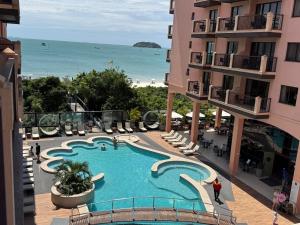 Una vista de una piscina con la playa al fondo. en Destino Floripa Jurerê, en Florianópolis
