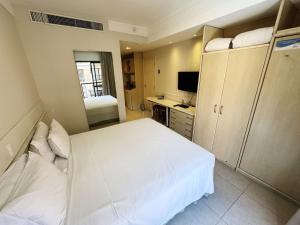 Un dormitorio con una cama blanca y un televisor. en Destino Floripa Jurerê, en Florianópolis 70 fotos más