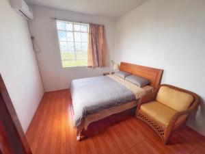 a bedroom with a bed and a chair and a window at 毛里求斯民宿 in Roche Bois