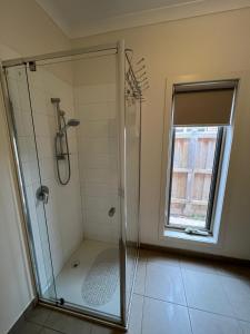 a bathroom with a glass shower with a window at My Home in Truganina
