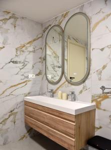 a bathroom with a sink and two mirrors at Apartments and Rooms Tomas in Podstrana
