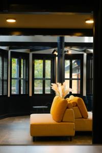 a yellow couch in a living room with windows at Fuji Elegance Hotel in Yamanakako