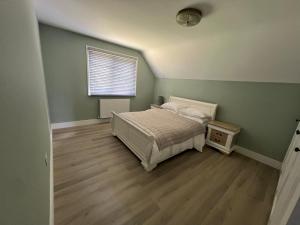a green bedroom with a bed and a window at Private Guest House with full kitchen living room and utility room Completely Separate from the Main House in Cobham