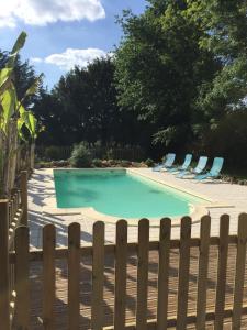 a swimming pool with chairs and a fence at Villa paisible avec piscine in Bercloux