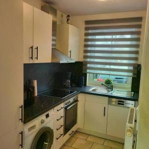 une cuisine avec des armoires blanches, un évier et un lave-vaisselle dans l'établissement Ferienhaus Pia, à Dorum Neufeld