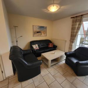 un salon avec des meubles en cuir noir et une table basse dans l'établissement Ferienhaus Pia, à Dorum Neufeld