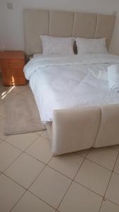 een wit bed bovenop een tegelvloer bij makao apartment in Nairobi